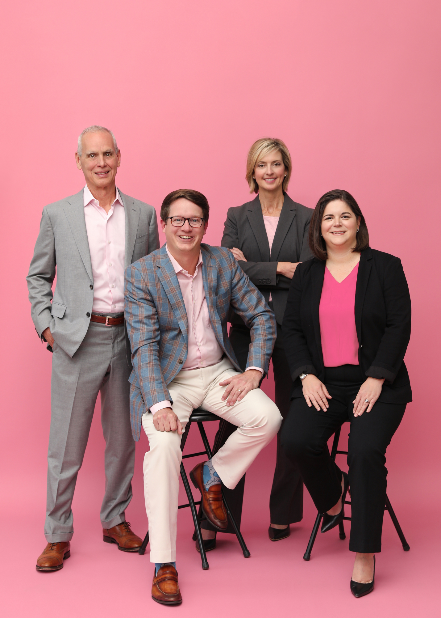 HHM CPA's two men and two ladies posing against pink background